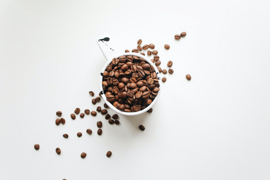 Coffee beans and mug on a white surface