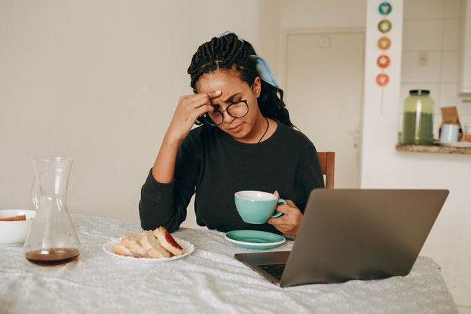 Woman holding a cup of CBD coffee while suffering from head pains