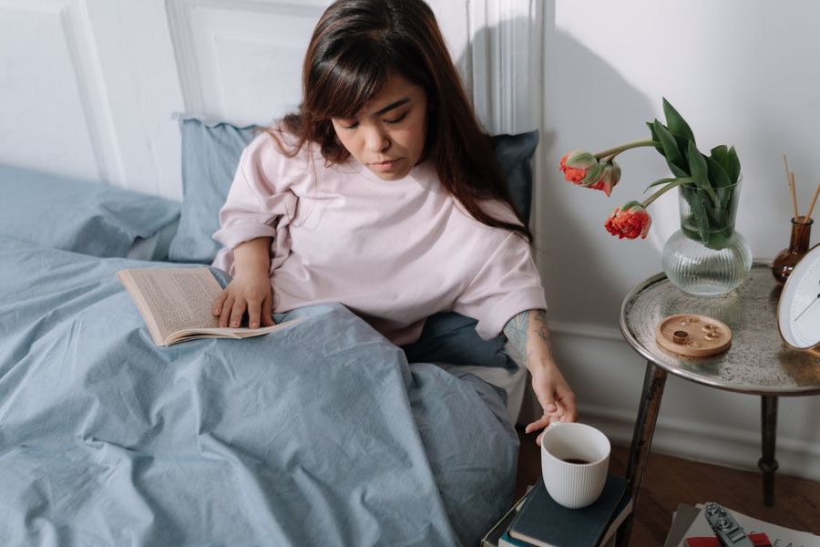 Woman sitting in bed while drinking a cup of CBD coffee